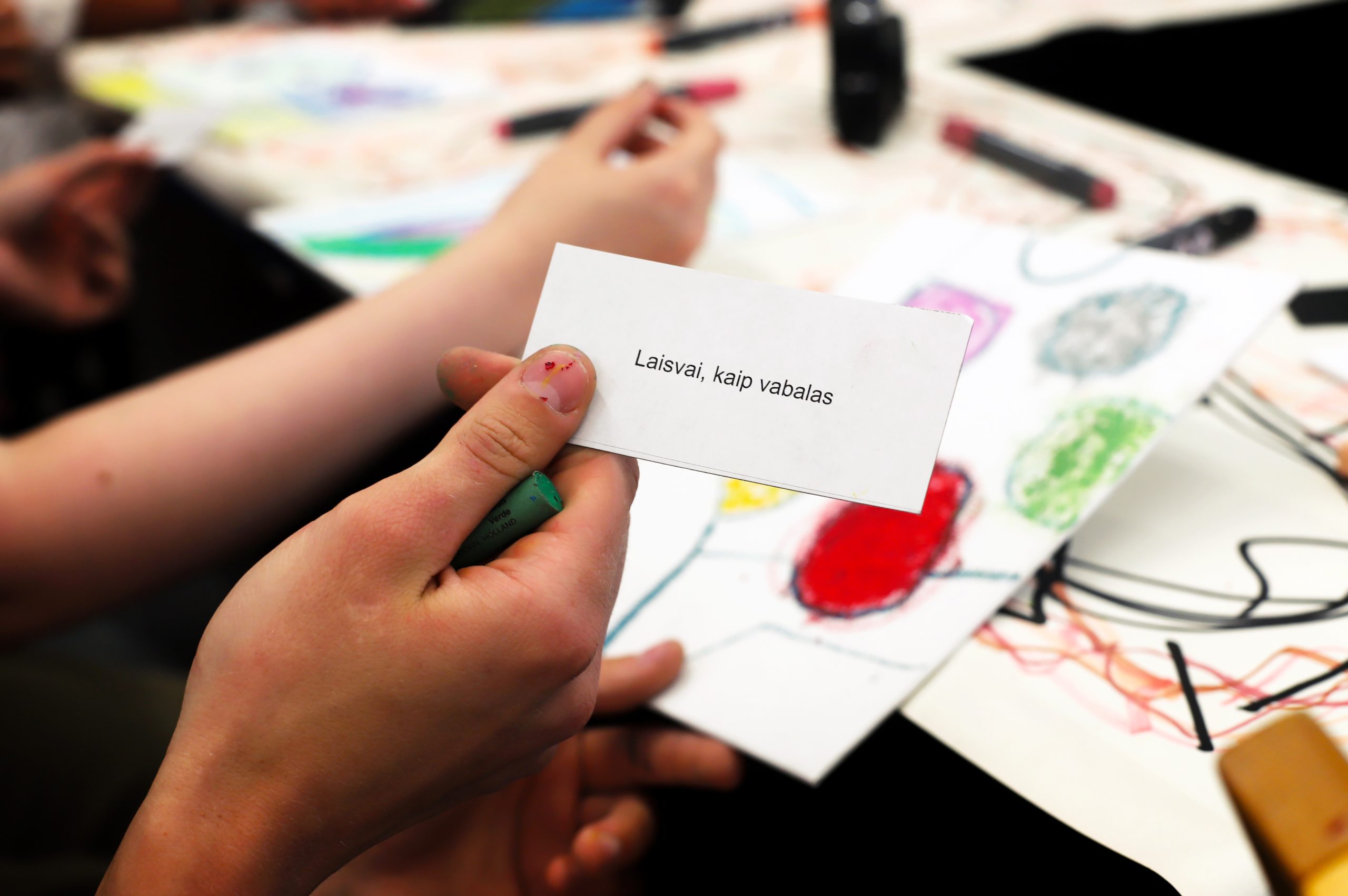 A hand holds a card reading Free, like a beetle in Lithuanian