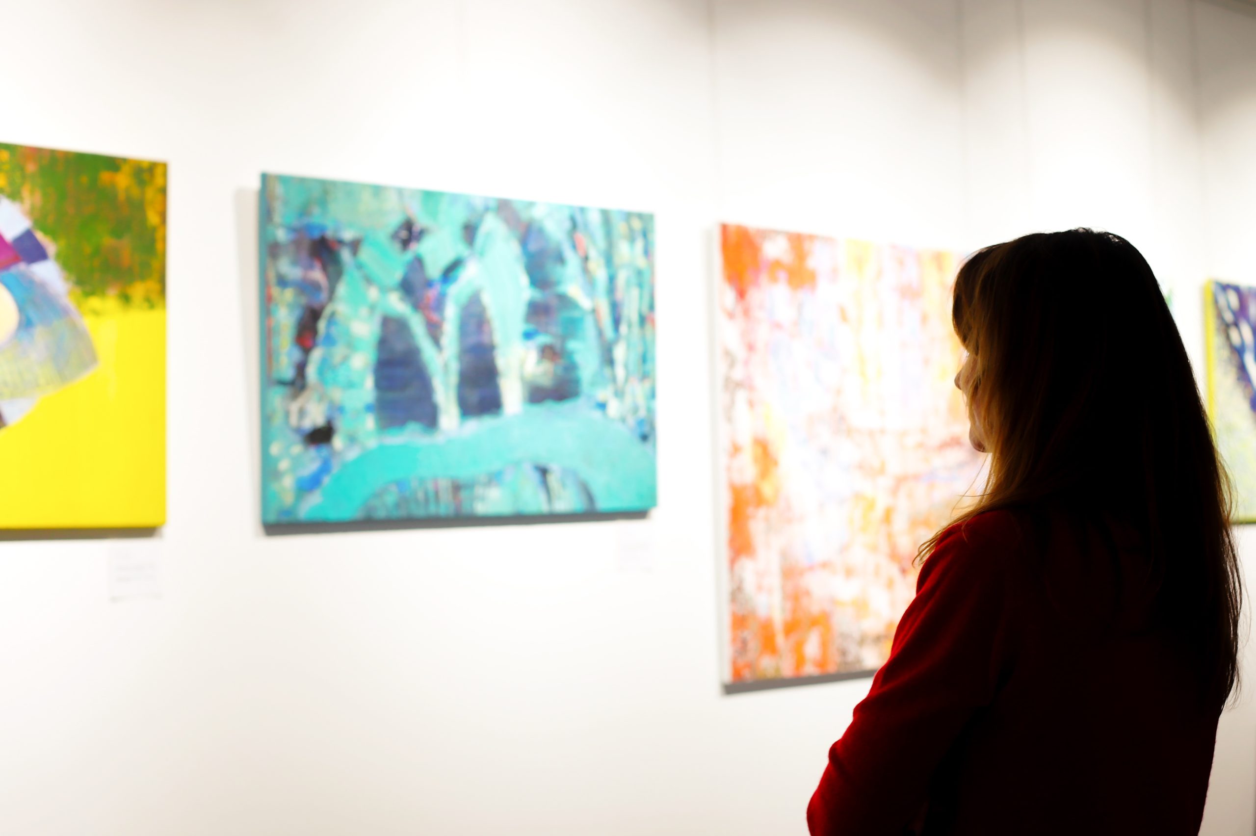 A visitor dressed in red looks at the paintings
